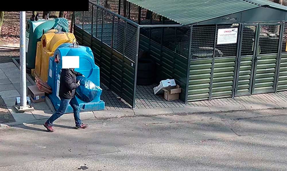 Kadr z monitoringu - osoba wynosi opony pod śmietnik. Zamazana twarz osoby.