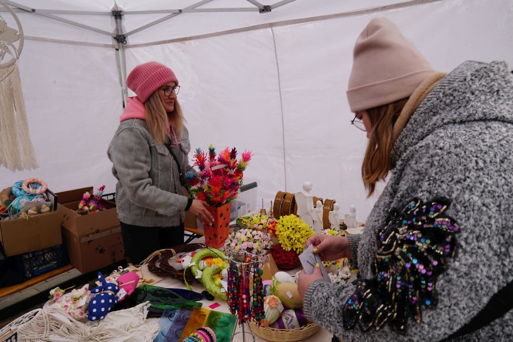 dwie kobiety oglądające rękodzieło w namiocie