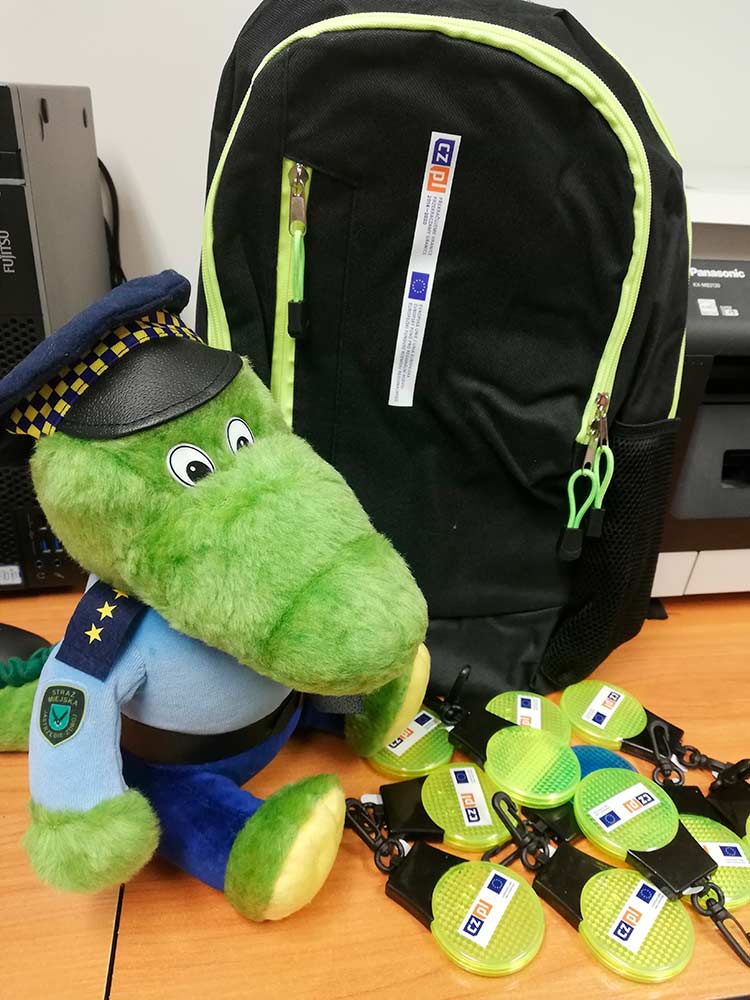 Zdjęcie przedstawia nagrody - maskotkę Smokusia, plecak i odblaski.
