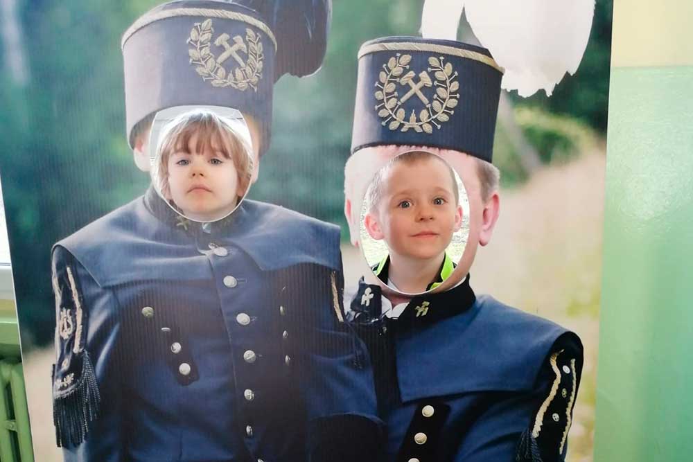 Dzieci robią sobie zdjęcie w planszy z górnikami (otwory w miejscach głów).