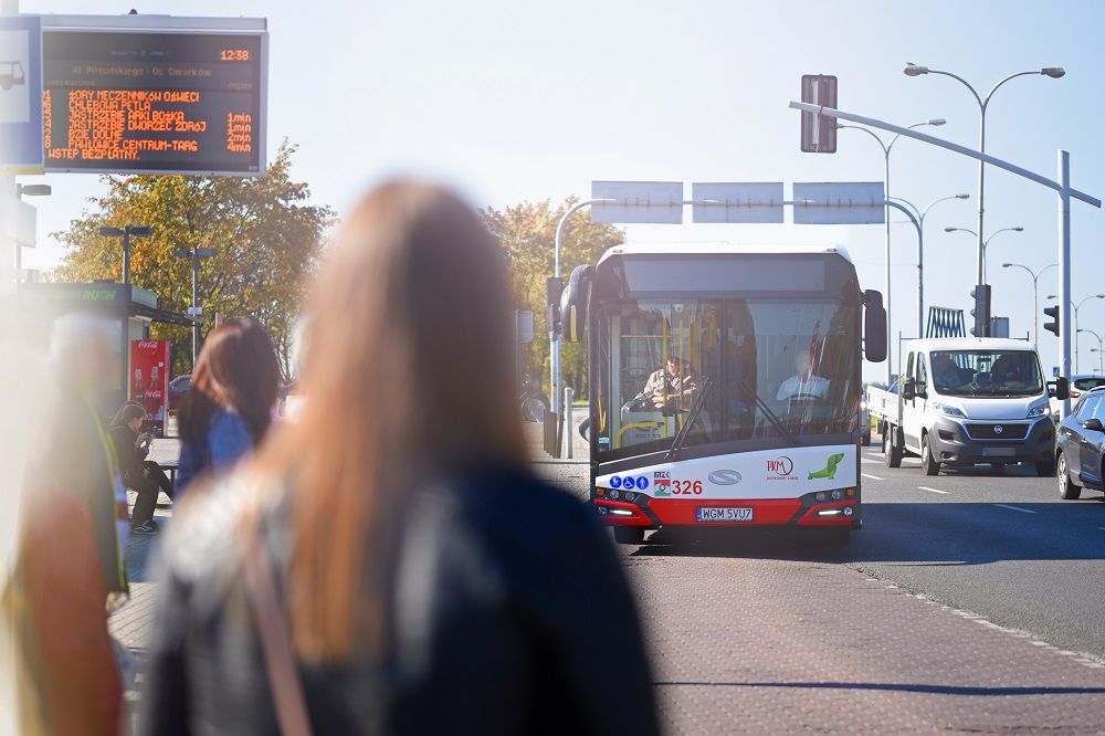 osoba stoi na przystanku autobusowym