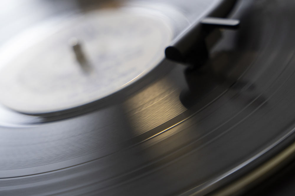 Zdjęcie przedstawia płytę analogową z opuszczonym na nią ramieniem gramofonu.