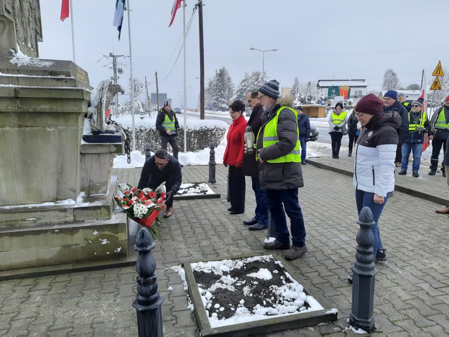 Zdjęcie przedstawia złożenie kwiatów przy Pomniku Niepodległościu w Bziu.