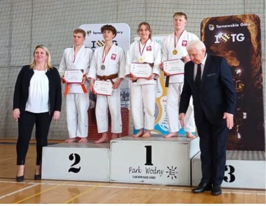 zawodnicy judo na podium, obok stoją działacze