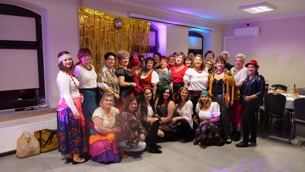 Grupowe zdjęcie uczestniczek biesiad, ubranych w różne kolorowe stroje
