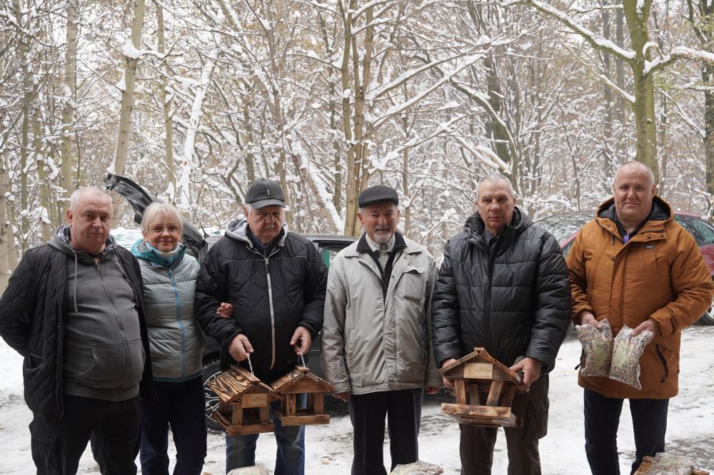 Zdjęcie przedstawia jastrzębskich działkowców z karmnikami i karmą dla ptaków.