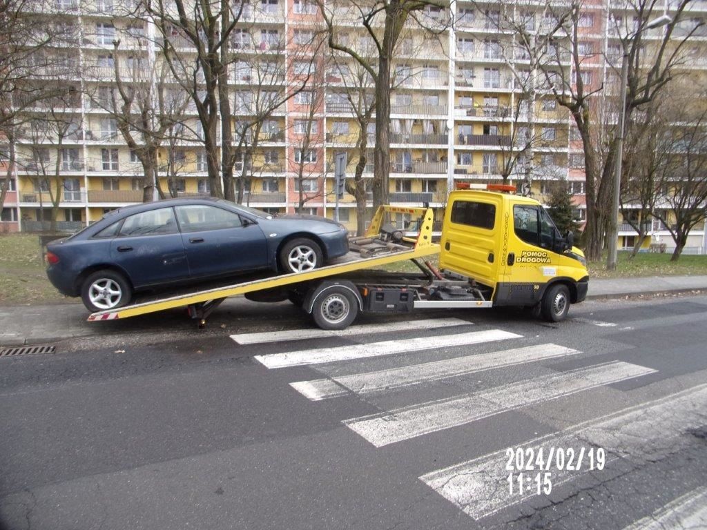 Zdjęcie przedstawia odholowany wrak samochodu.