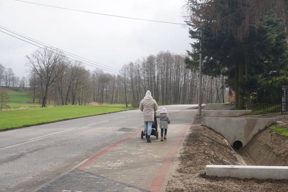 Zdjęcie przedstawia spacerujących ludzi na wyremontowanym chodniku. 