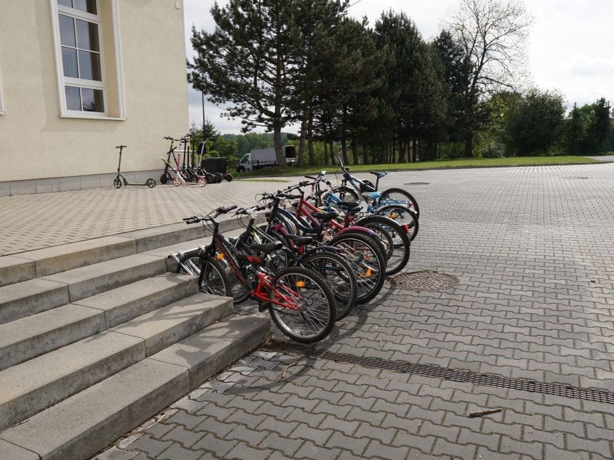 Plakat przedstawia rowery przy szkole podczas kampanii "Rowerowy Maj"