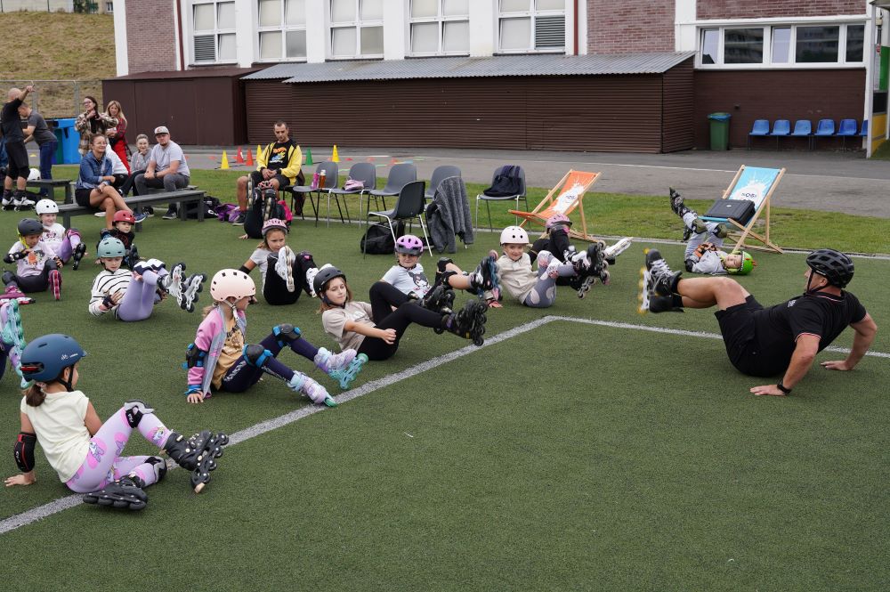 Grupa młodych rolkarz leżąca na boisku podczas rozgrzewki