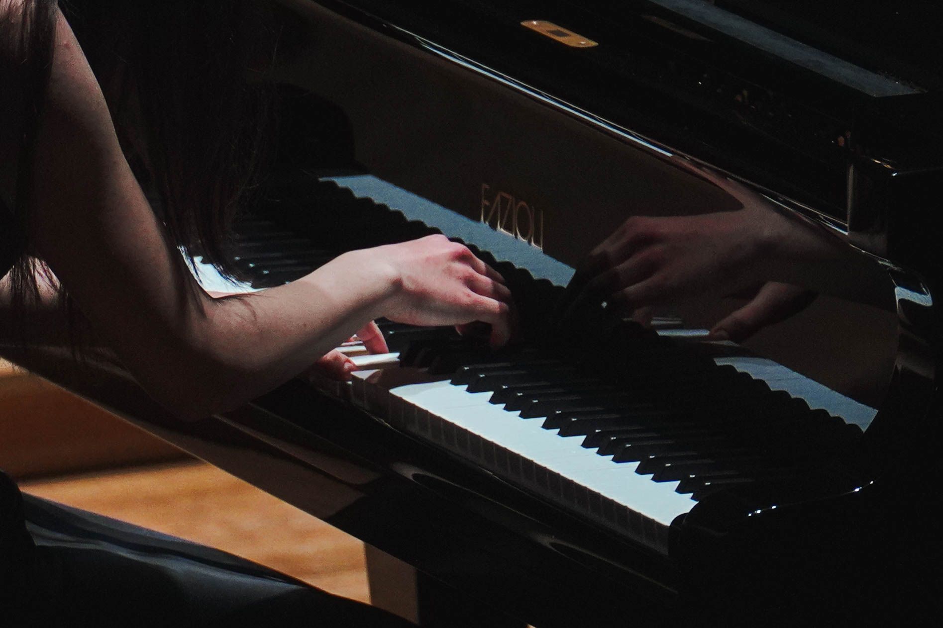 Bliskie ujęcie na klawiaturę fortepianu i dłonie artystki