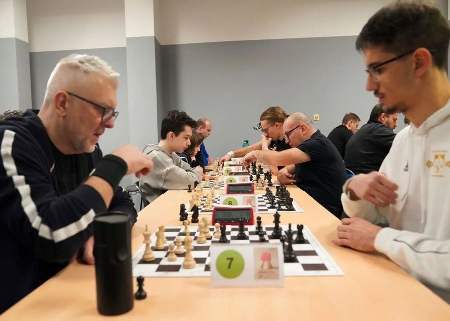 zawodnicy siedzą przy szachownicach