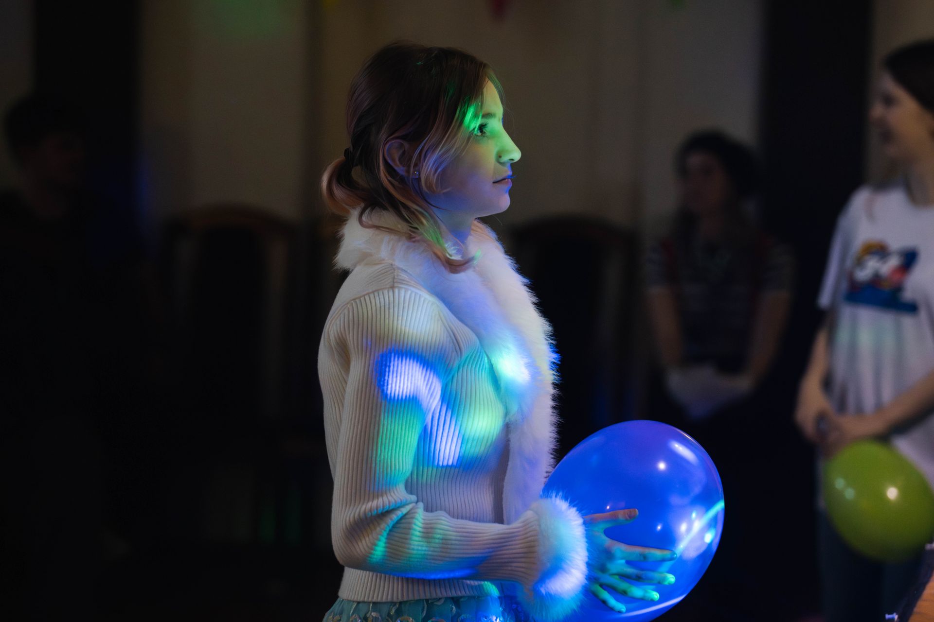 dziewczynka w białym stroju trzyma w rękach niebieski balon