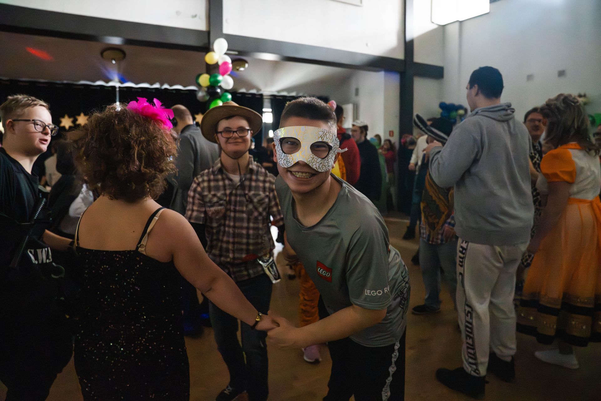 chłopak w białej masce uśmiecha się do zdjęcia podczas tańca